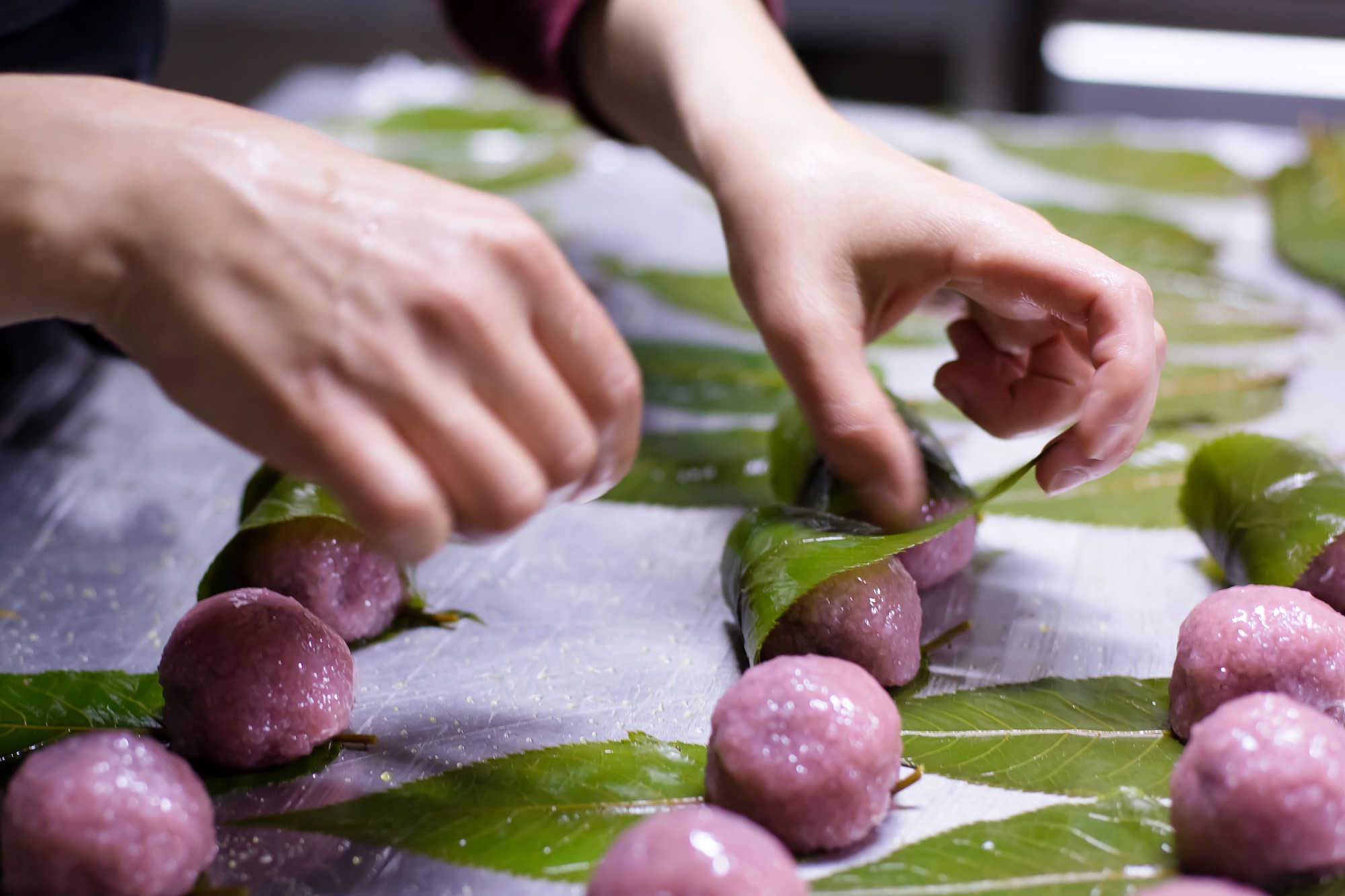 Production of sakura mochi, a spring wagashi with cherry blossom leaves.